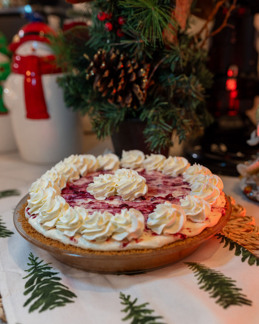 A berry cream pie topped with piped whipped cream, on a holiday table at home