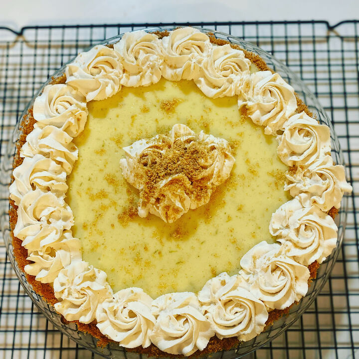 Key lime pie on a graham crust ringed with piped whipped cream rosettes