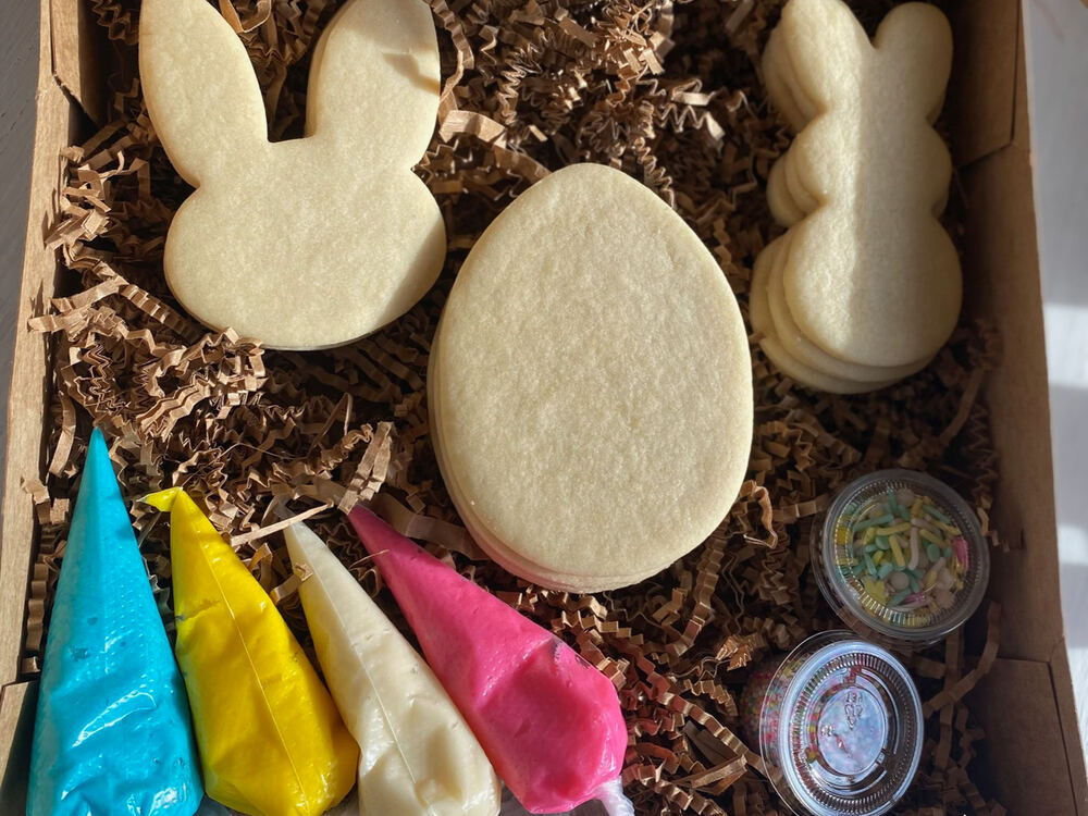 Easter cookie kit: undecorated bunny and egg sugar cookies boxed with four piping bags of frosting and pots of sprinkles